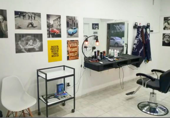 Interior de CRONO con sillón de barbero, espejo, mesada de herramientas y cuadros en la pared